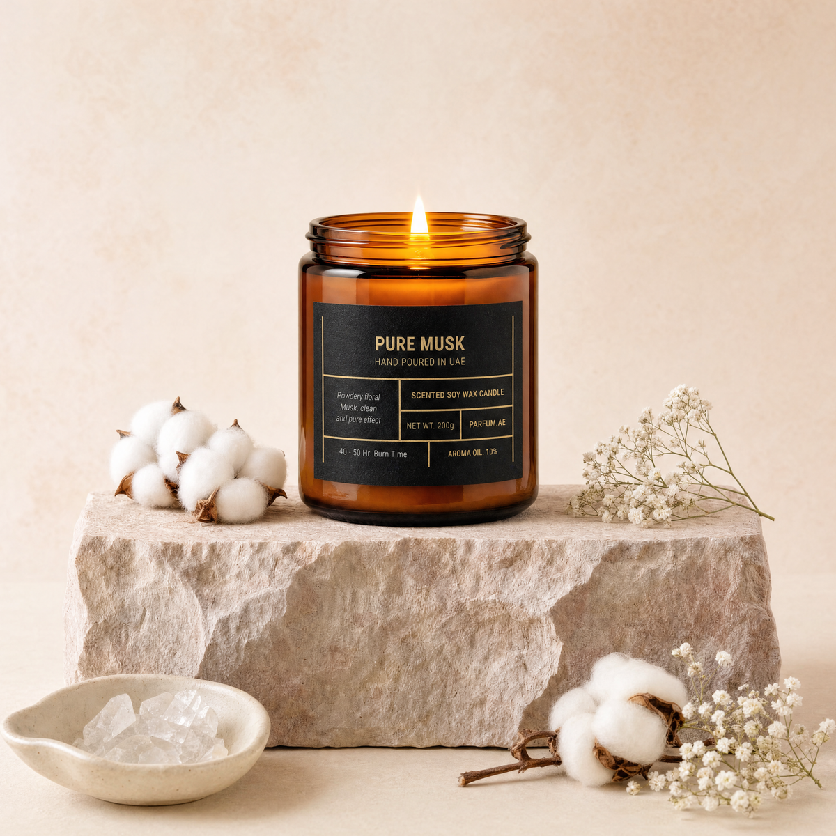 Pure Musk scented soy wax candle, lit, on travertine stone with cotton, baby's breath and white quartz